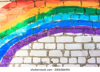 A rainbow painted on white brick wall. Red, orange, yellow, green, blue, indigo, purple colors. Gay LGBT flag, pride. International day of happiness. 