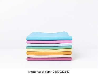 rainbow and pastel toned clothes stacked on top of each other, cleanly ironed and folded on white background isolated - Powered by Shutterstock