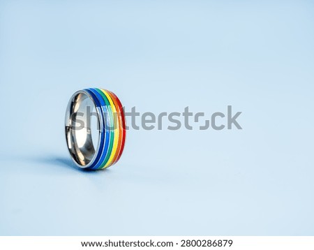 Rainbow pride ring on blue background with space. LGBTQ+ pride, diversity, equality, inclusion, love, acceptance, human rights, identity, community support, and social awareness with ample copy space.