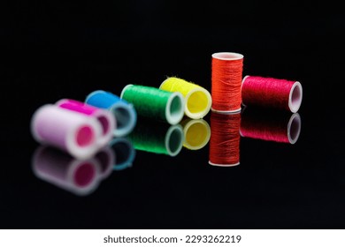 Rainbow sewing threads staring orange on black background