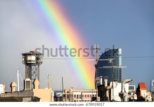 a rainbow in the sky after a storm over the skyline\
of barcelona city