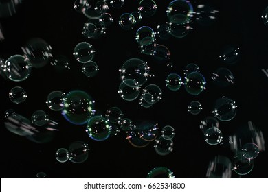 Rainbow soap bubbles on a dark background.