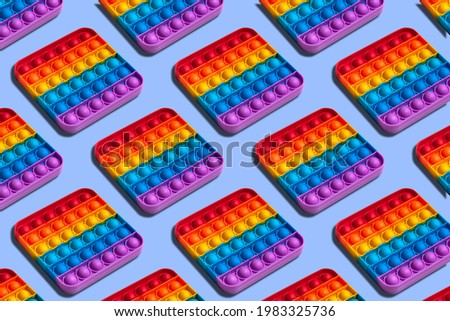 Rainbow square shape isometric pattern of silicon toy for kids. Pop it fidget toy on pastel background. Simle dimple toy on blue pastel background. 