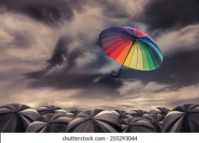 rainbow umbrella fly out the mass of black umbrellas - Powered by Shutterstock