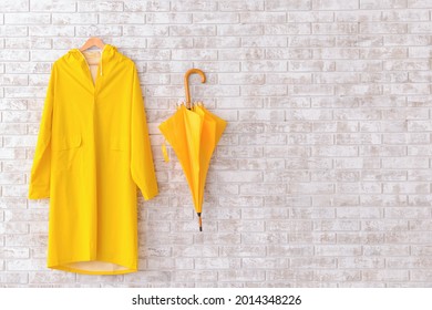 Raincoat and umbrella on brick background