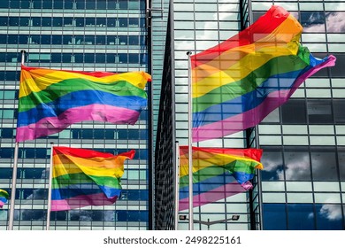 Raindbow flags in front of modern architecture of Amsterdam, the Netherlands, Europe.