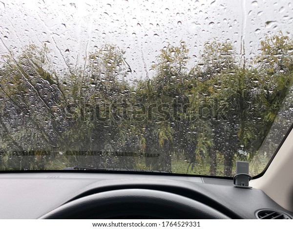 Raindrop on the car rear view mirror and car\
glass. Heavy rain\
outside