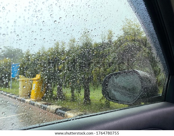 Raindrop on the car rear view mirror and car\
glass. Heavy rain\
outside