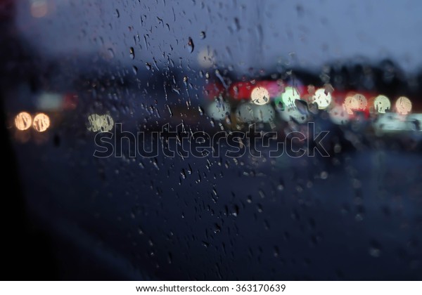 Raindrop on the window at night with colorful\
light on the street