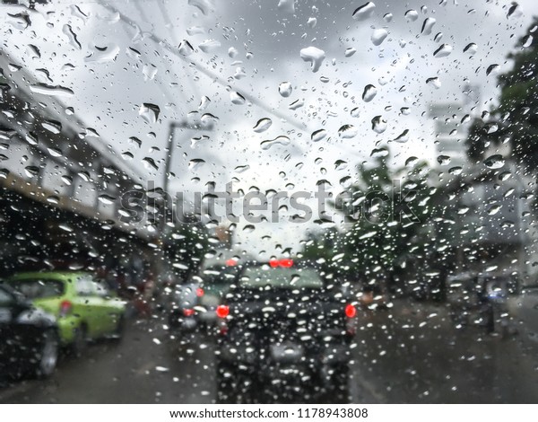 Raindrop outside the car in raining\
day for background at Street traffic of working day in rainy day\
thailand.Good view from driver seat.Selective\
focus.