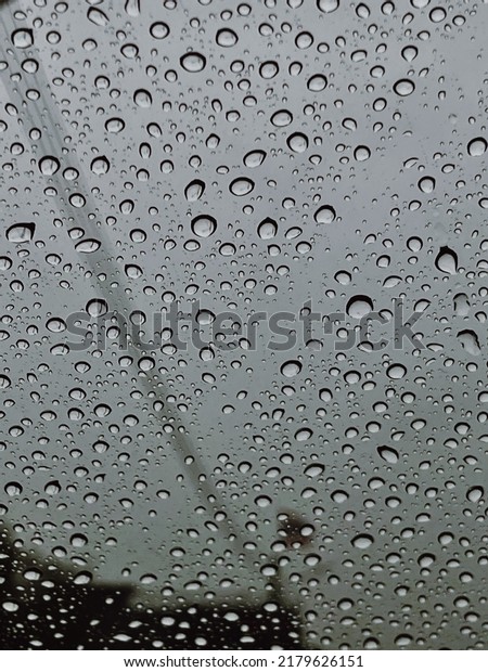 Raindrop outside the car in raining day for\
background at Street traffic of working day in rainy day. Good view\
from driver seat. Selective\
focus.