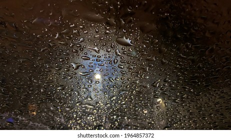 Raindrops Dripping On The Glass Of The Car, Macro. Light In The Window. Night Time