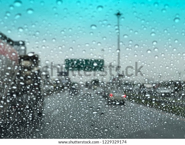 Raindrops falling on the car windshield,\
traffic in the city on a rainy day, car windshield view, colorful\
bokeh. Blurred\
background.
