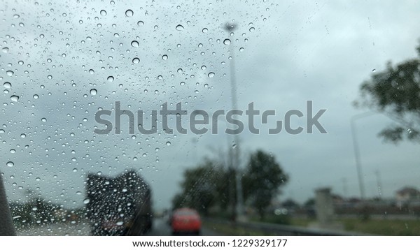 Raindrops falling on the car windshield,\
traffic in the city on a rainy day, car windshield view, colorful\
bokeh. Blurred\
background.