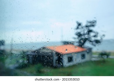 The raindrops falling on the windows are a view of a house against the backdrop of a hazy beach. Selective focus. - Powered by Shutterstock