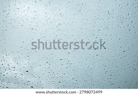 Raindrops gather on a window during a cloudy day in an urban setting