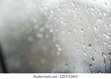 Raindrops gracefully dance on a window pane, reflecting a moody rainy day. Symbolizing introspection, renewal, and nature's serene beauty