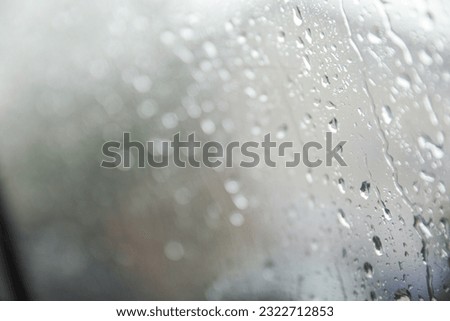 Raindrops gracefully dance on a window pane, reflecting a moody rainy day. Symbolizing introspection, renewal, and nature's serene beauty