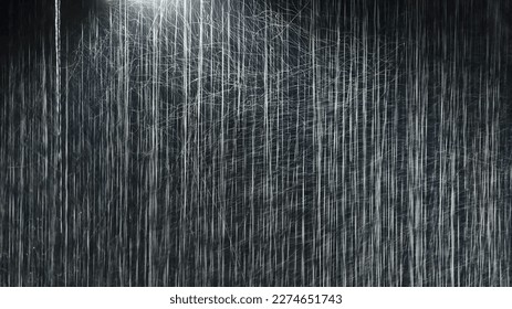 Raindrops illuminated by a street lamp during a downpour on a dark background. Atmospheric natural texture