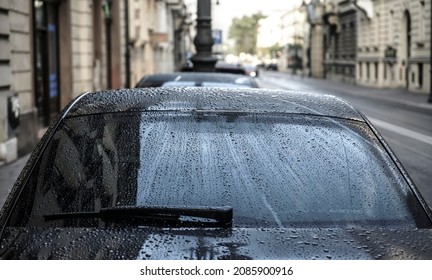 Raindrops On A Back Car Glass. On A Cloudy, Rainy Day, The Back Window And Windshield Wiper Of A Car Are Covered With Drops Of Torrential Rain. Sadness. Melancholy. Bad Weather.