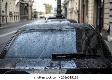 Raindrops On A Back Car Glass. On A Cloudy, Rainy Day, The Back Window And Windshield Wiper Of A Car Are Covered With Drops Of Torrential Rain. Sadness. Melancholy. Bad Weather.