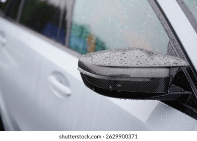 raindrops on black side mirror of modern white car. close-up detail highlights texture and design, capturing sleek automotive aesthetics and weather conditions driving mood