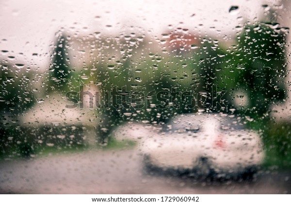 Raindrops on a car glass against
a blurred background with a view of the city and the lights of
cars.