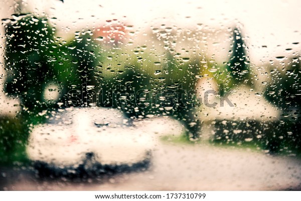 Raindrops on a car glass against\
a blurred background with a view of the city and the lights of\
cars.