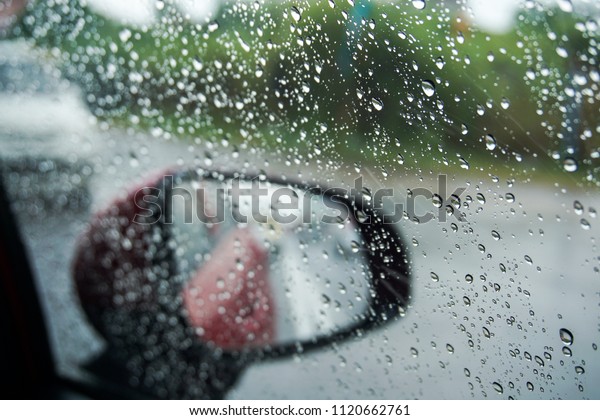 Raindrops on the car rear view mirror. Heavy\
rain on monsoon season in\
Malaysia.