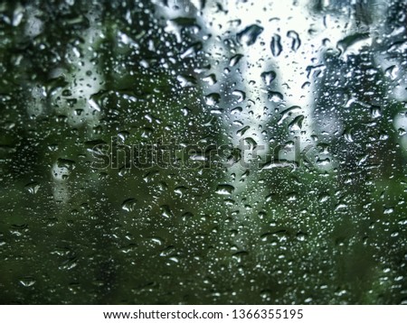 Raindrops on the car window. Blurred background of spring forest