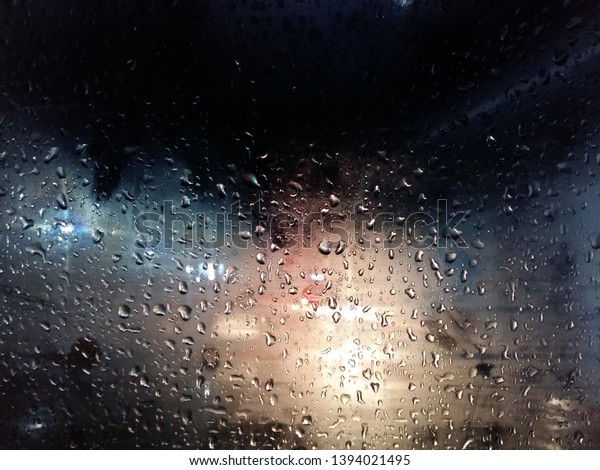 Raindrops on a car window at night,
illuminated by car
headlights.