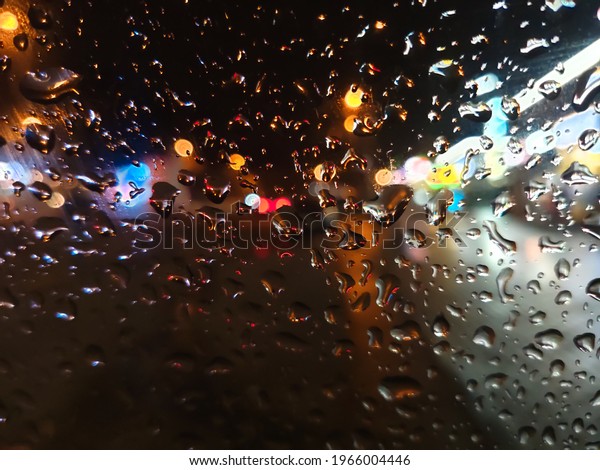 Raindrops on the\
car window in the night city against the background of glowing\
signs of shops and passing\
cars