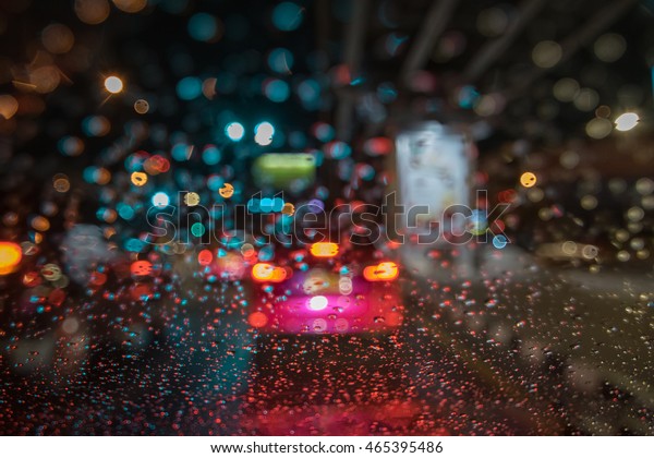 Raindrops on car window at night in the city.\
Blurred background