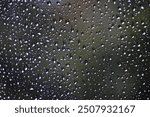 Raindrops on the car windshield during the rainy season. Raindrops of various sizes line up, creating a beautiful and unusual sight. 