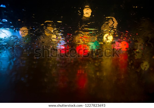 Raindrops on the glass on the background of\
street lights. Blurred\
background.