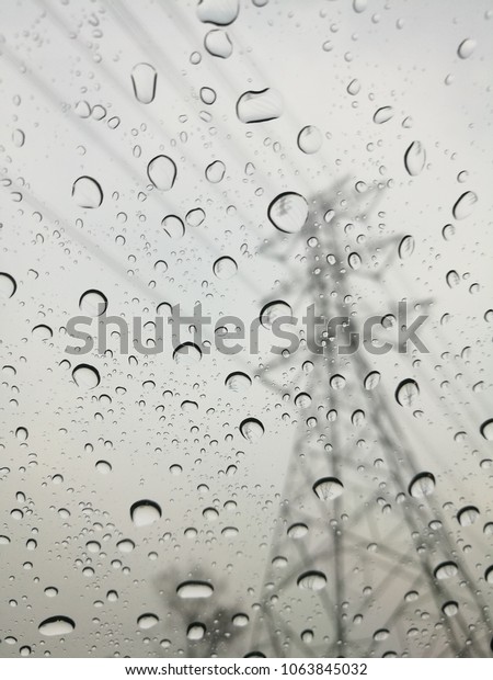 Raindrops on glass with\
high voltage electrical pole and raining around high voltage tower\
Texture Background