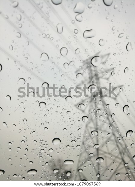 Raindrops on glass with\
high voltage electrical pole and raining around high voltage tower\
Texture Background