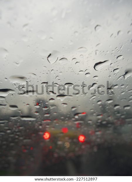 Raindrops on glass. Outside window evening on\
street traffic with car\
light.
