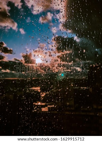 Raindrops on the glass of window against the sky with clouds. The sun after the rain. Amazing view

