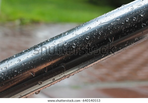 Raindrops on the railing of the stairs. Stair\
handrail is made of stainless\
steel