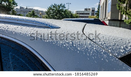 Raindrops on the roof of a white car.