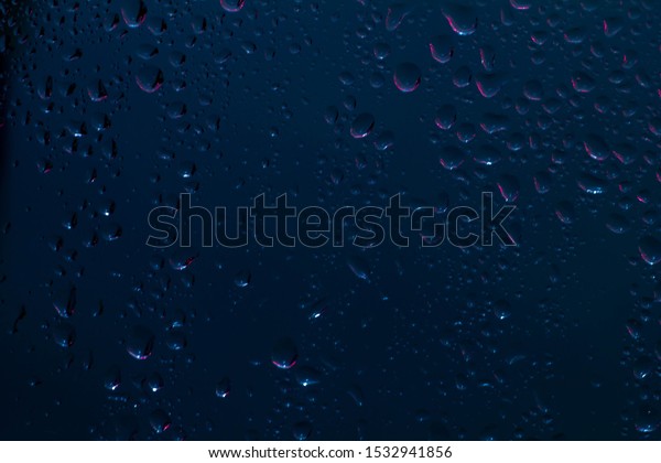 Raindrops on the surface of window panes\
Natural pattern of raindrops, on a blue\
background.