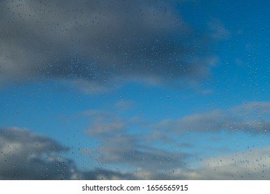 Raindrops on a window and a cloudy sky during rainy weather.