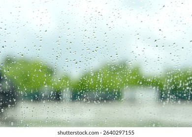 Raindrops on a window creating a blurry view of the outdoors