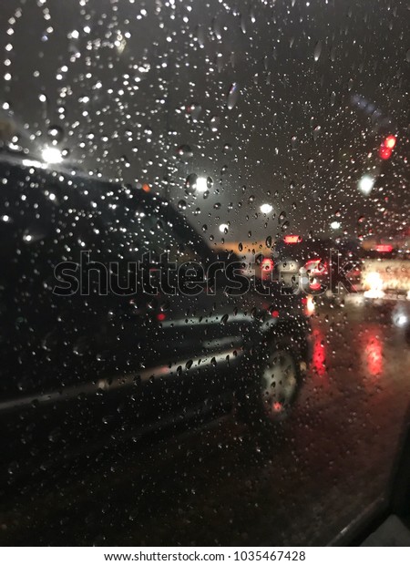 Raindrops on window glass and car traffic with\
bokeh background at\
night