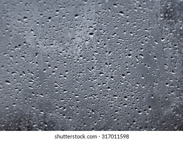 Raindrops on a window pane on the background of a stormy sky.