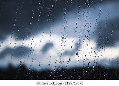 Raindrops On The Window Pane. Black, Gray, White Gradient On Blurry Background. Cloudy Rainy Weather Outside The Window. Cooling, Raining, Bad Weather Forecast