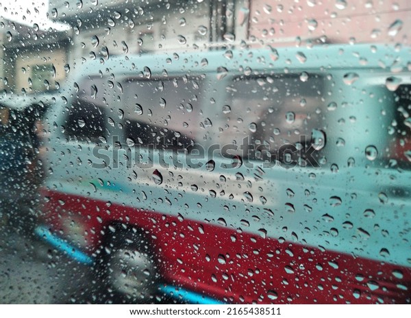 Raindrops on a window with a public\
transport car in the background in Jakarta,\
Indonesia