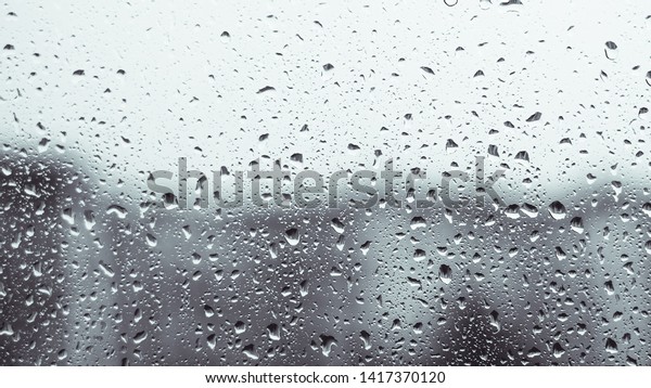 raindrops on a window. Rainy window at\
night. Drops on the black glass. dark blue wet, drops of water rain\
on glass background. concept of autumn\
weather.