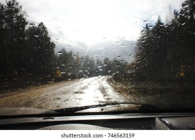 Raindrops on the windshield on the blurred background of a country road